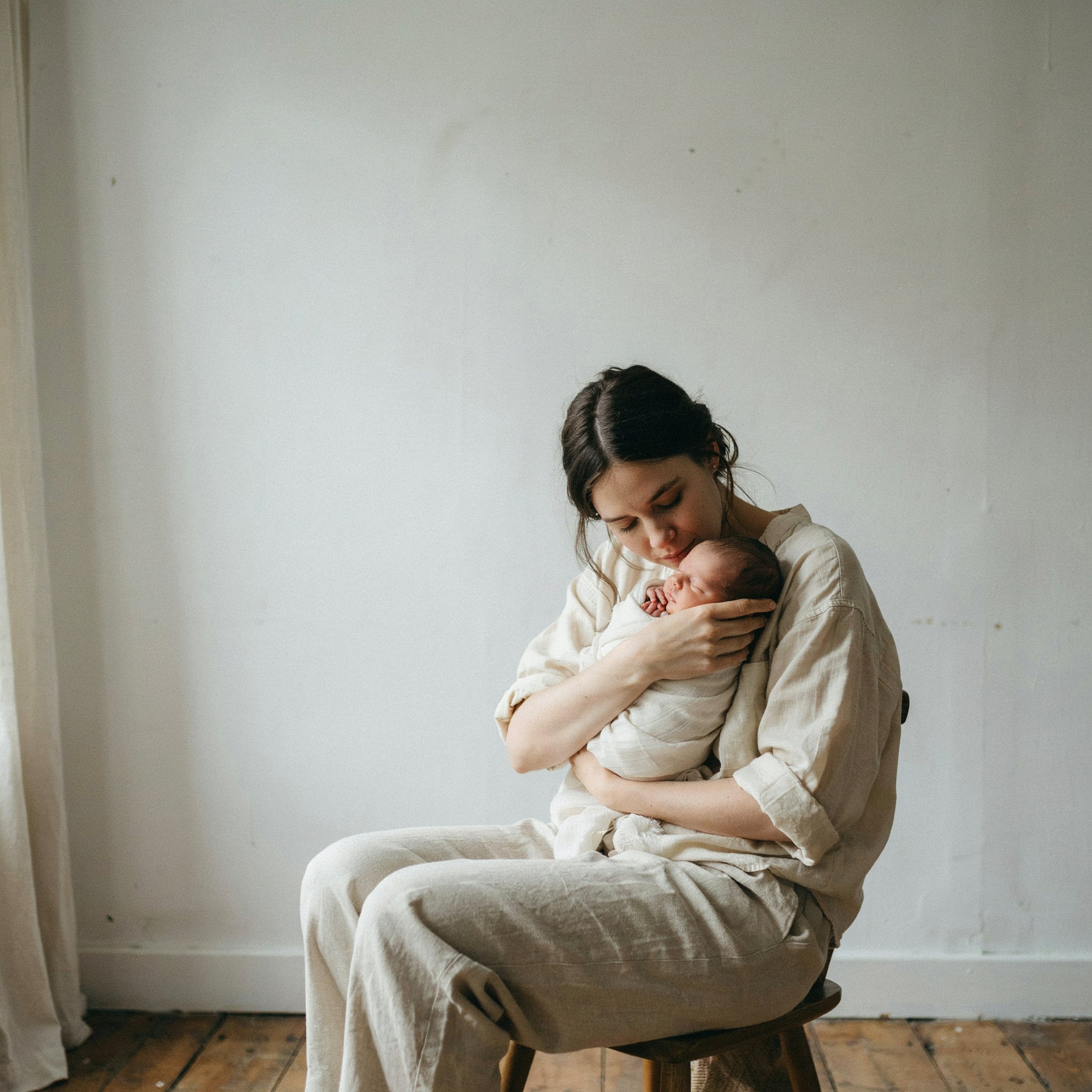 A mother cradling her infant in soft natural light